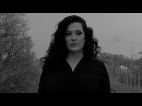 Kelsey Rae Copeland in a black dress standing in an open field at dusk